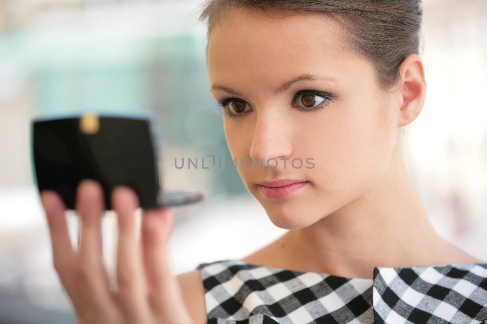 beautiful girl looks at itself in mirror and values make-up
