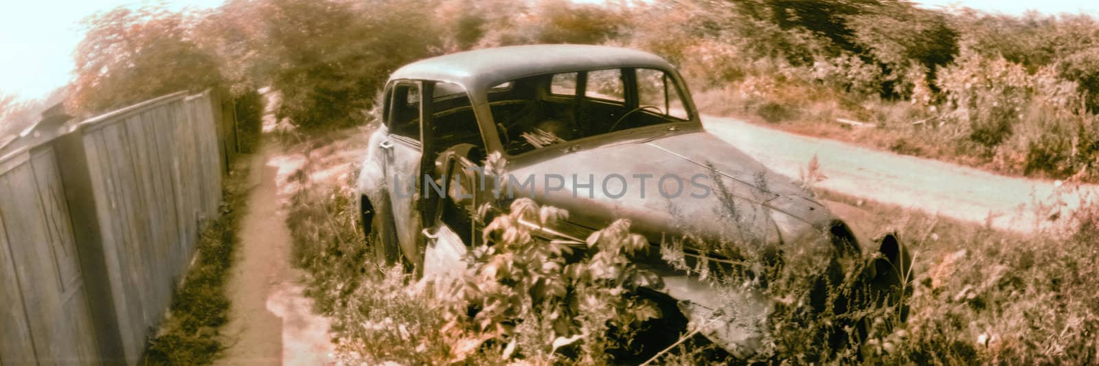 The old deserted automobile at a fence in a countryside