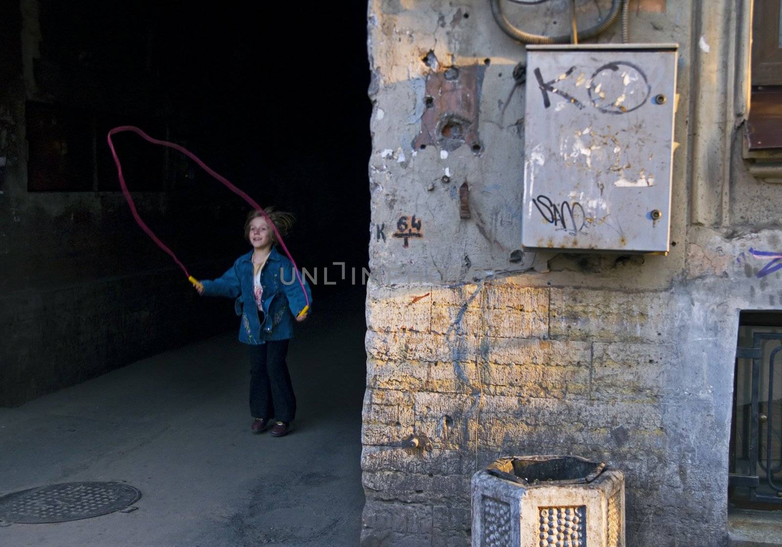 ST PETERSBURG, RUSSIA-APRIL, 2008: Small girl playing jumping rope in poor area in city outskirts in Saint Petersburg, Russia