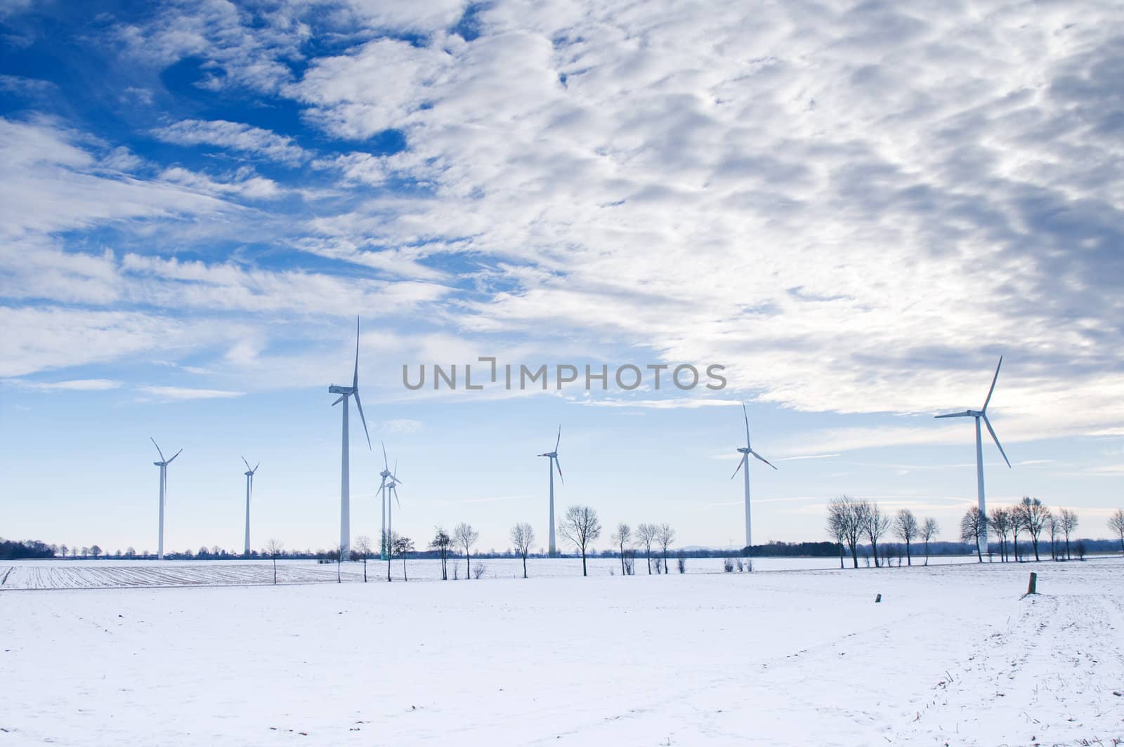 winter windmill park in a white snow landscape with blue sky and clouds
