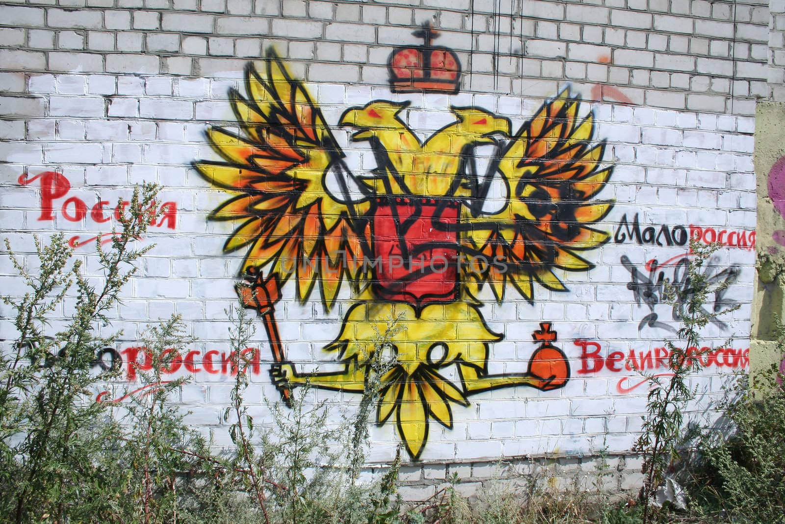 The arms of Russia as graffiti drawn on a white brick fence
