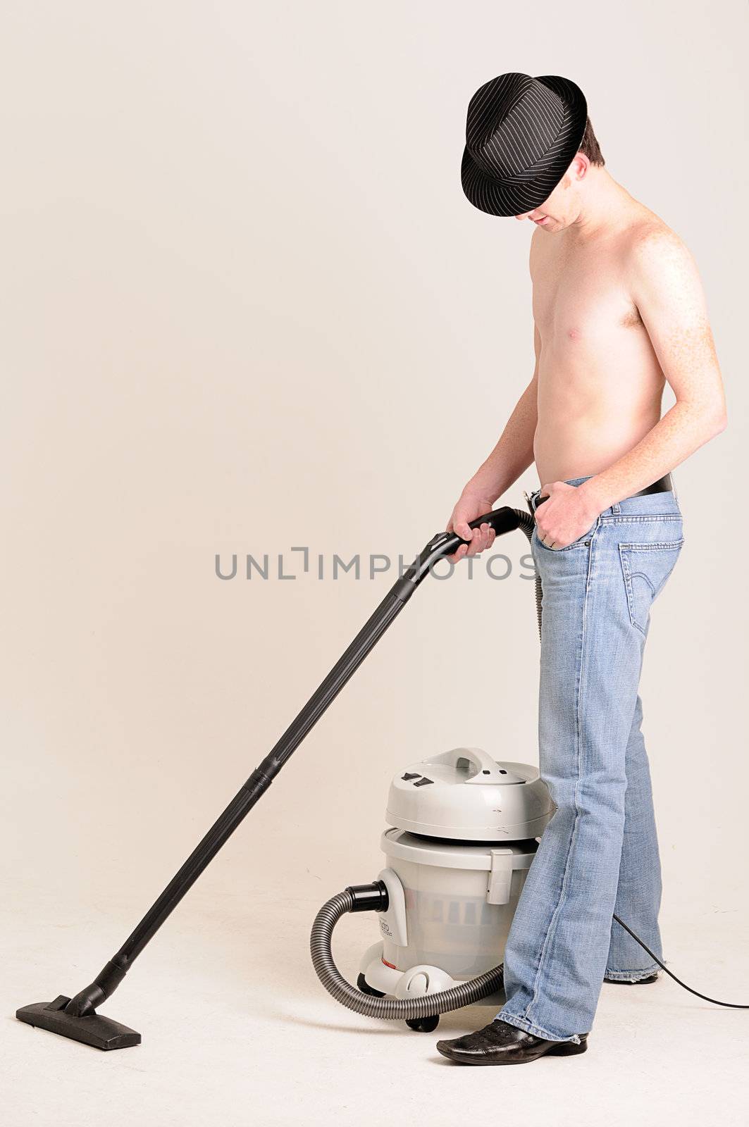 young man doing work at home with a vacuum cleaner without a shirt on