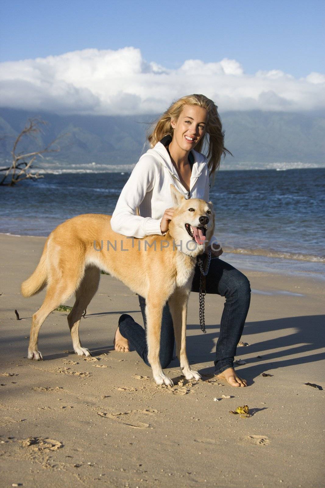 Caucasian woman with brown dog on leash on Maui, Hawaii beach.