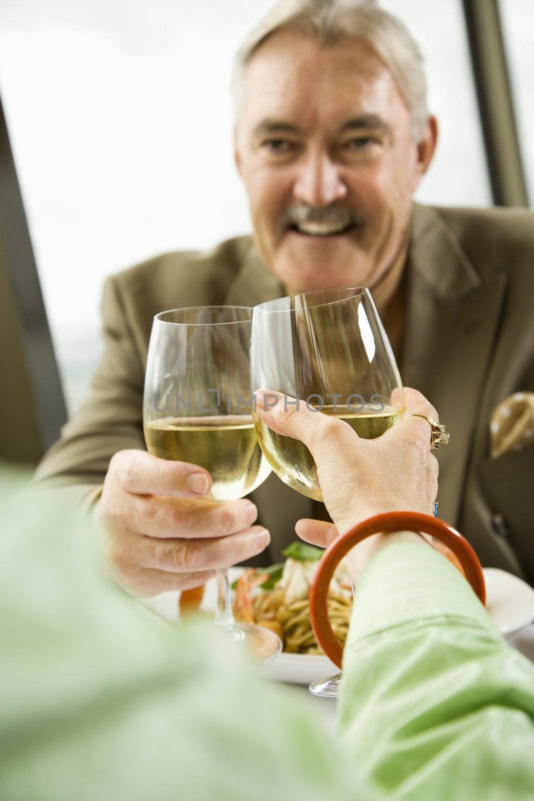 Mature couple dining and toasting in fancy restaurant.