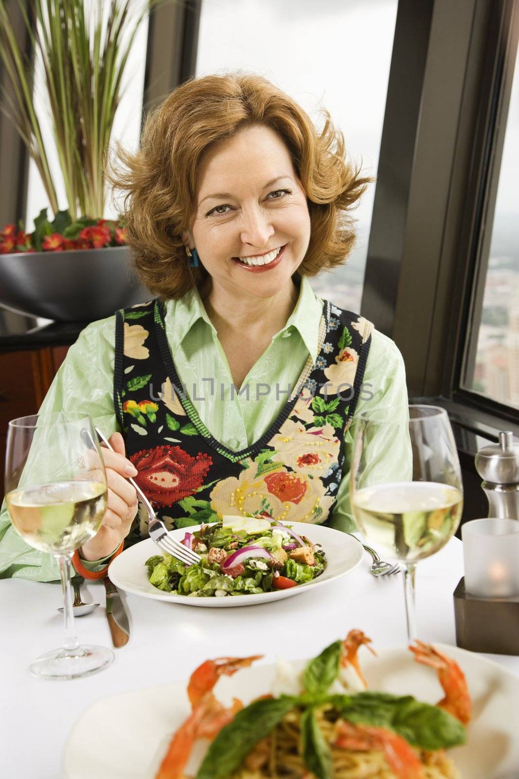 Caucasian mature woman with meal in restaurant smiling.