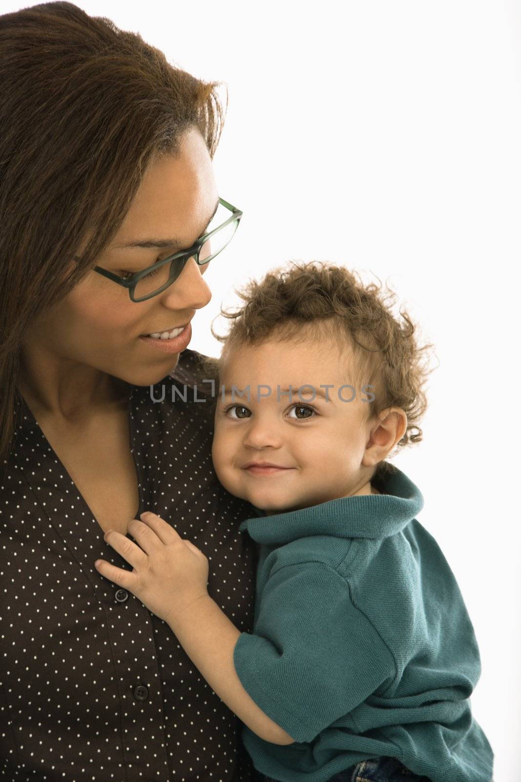 African American mid adult mom holding toddler son who is looking at viewer.