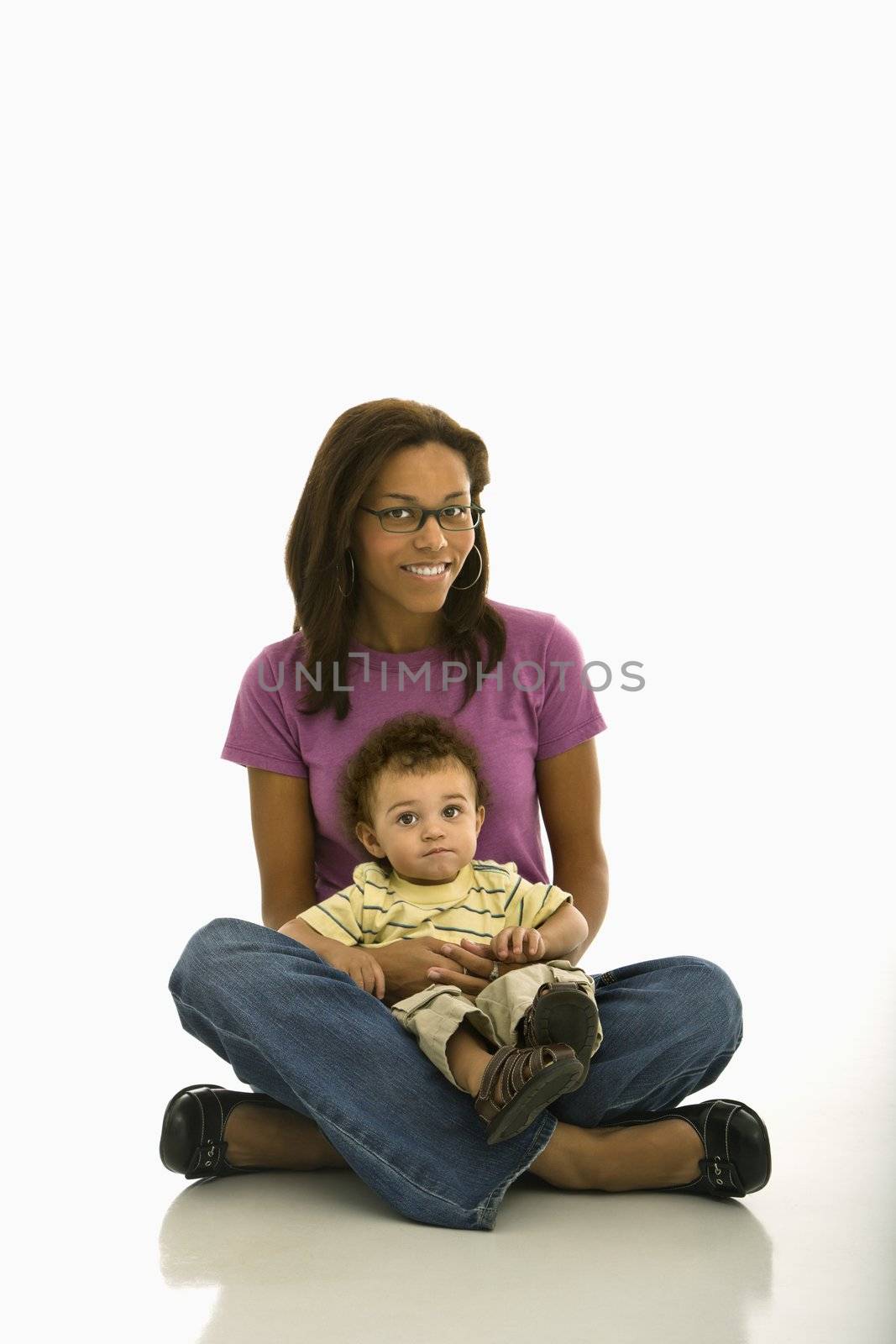 African American mid adult mom sitting with toddler son on lap looking at viewer.