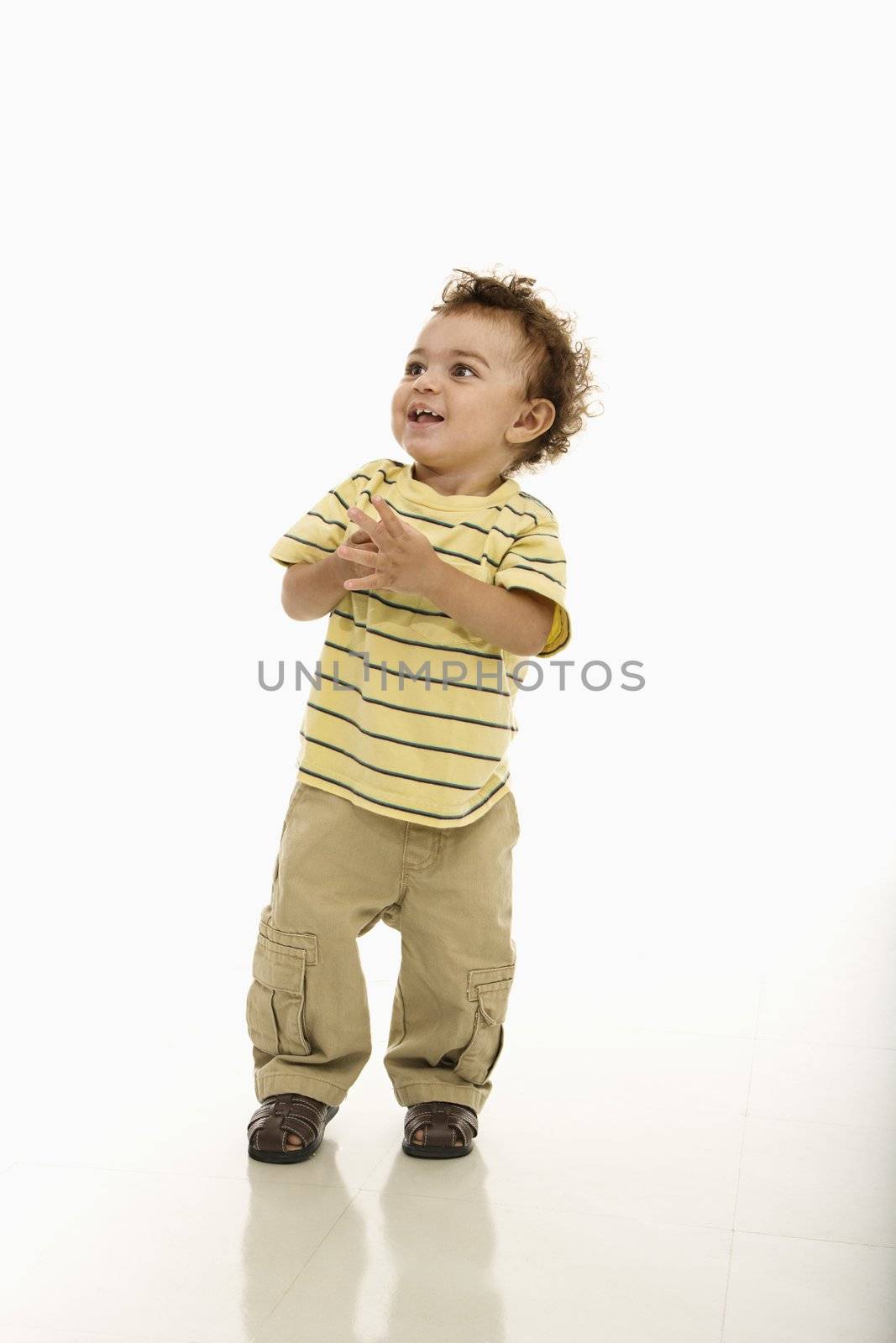 African American toddler boy standing with hands together and happy expression.