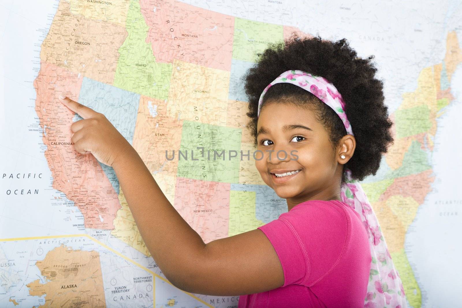 African American girl pointing to map of United States and smiling at viewer.