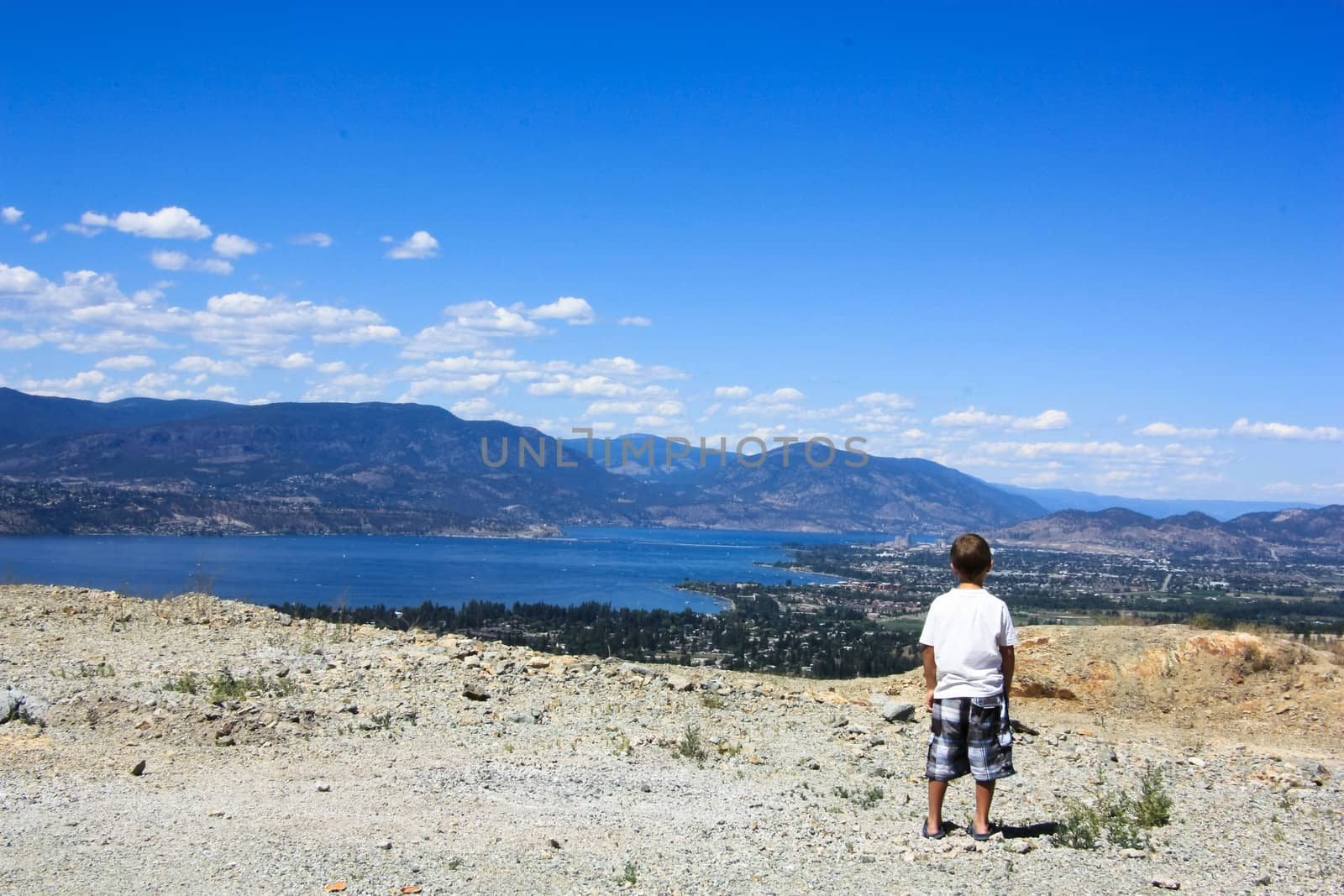 photo of a boy watching horizon from the mountain in a sunny summer day
