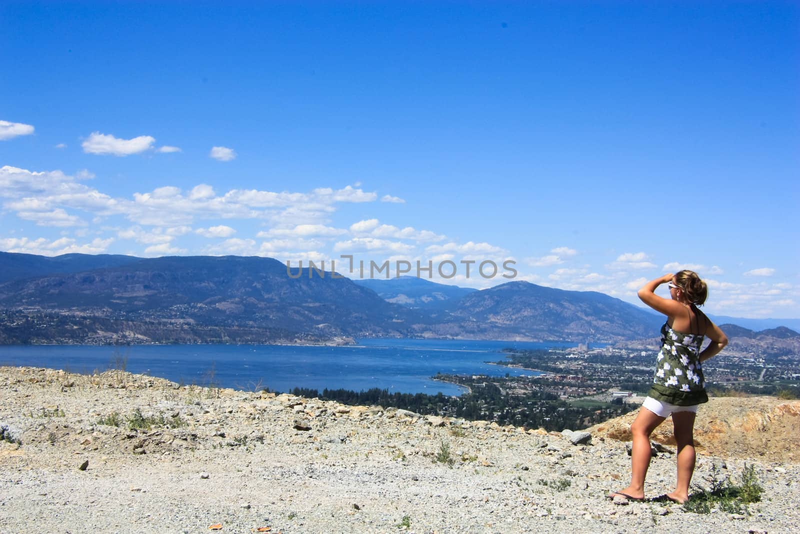 photo of a girl watching horizon from the mountain in a sunny summer day
