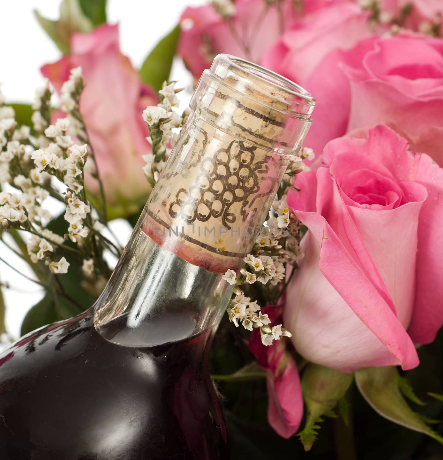 Closeup view of a corked bottle of champagne and some pink roses