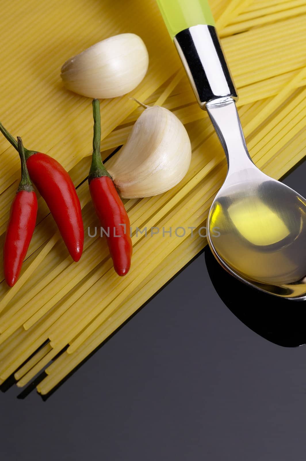 pasta garlic olive oil and red chili pepper ove black reflective surface