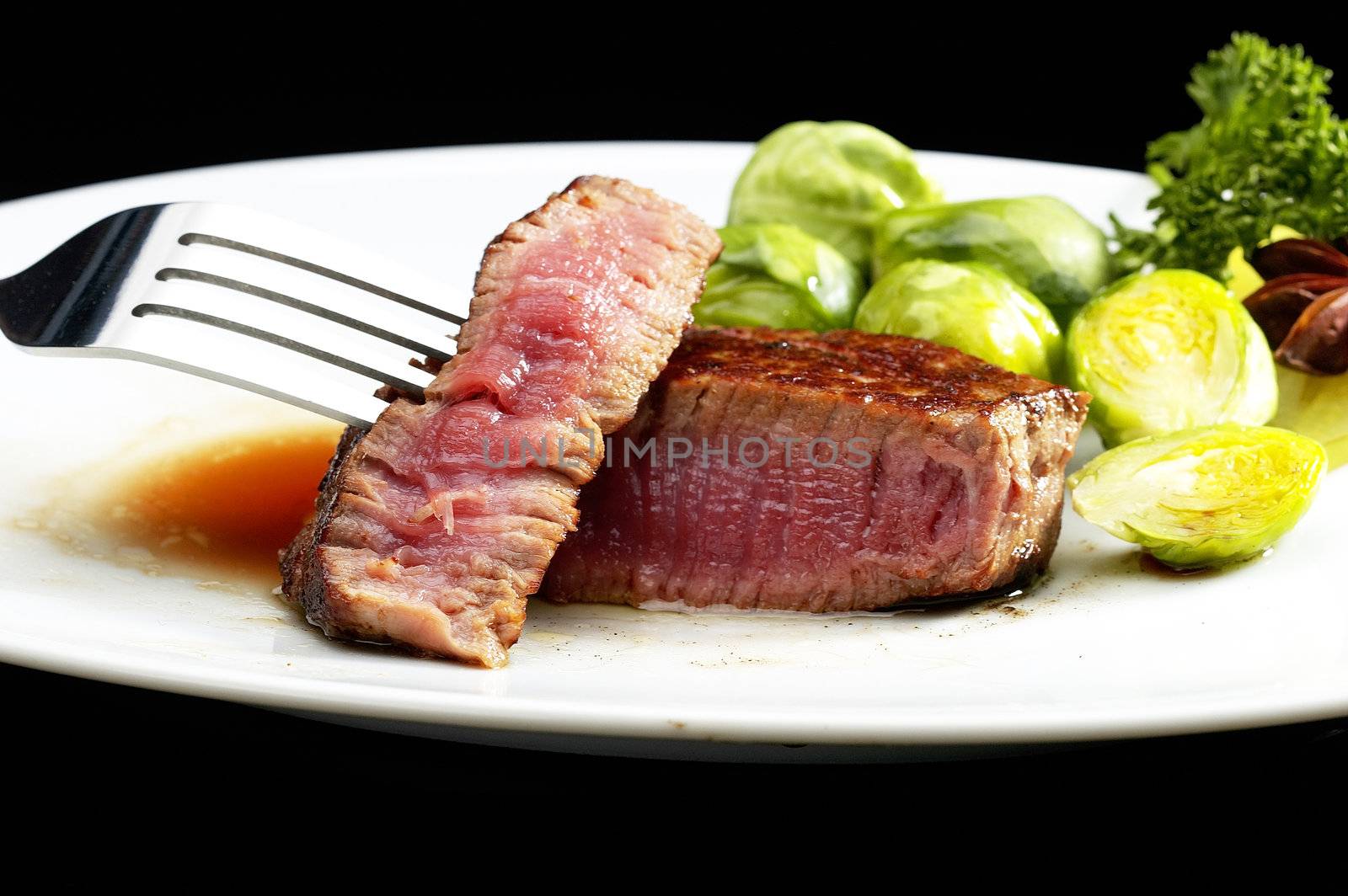 juicy filet mignon on plate with brussel sprout over black background