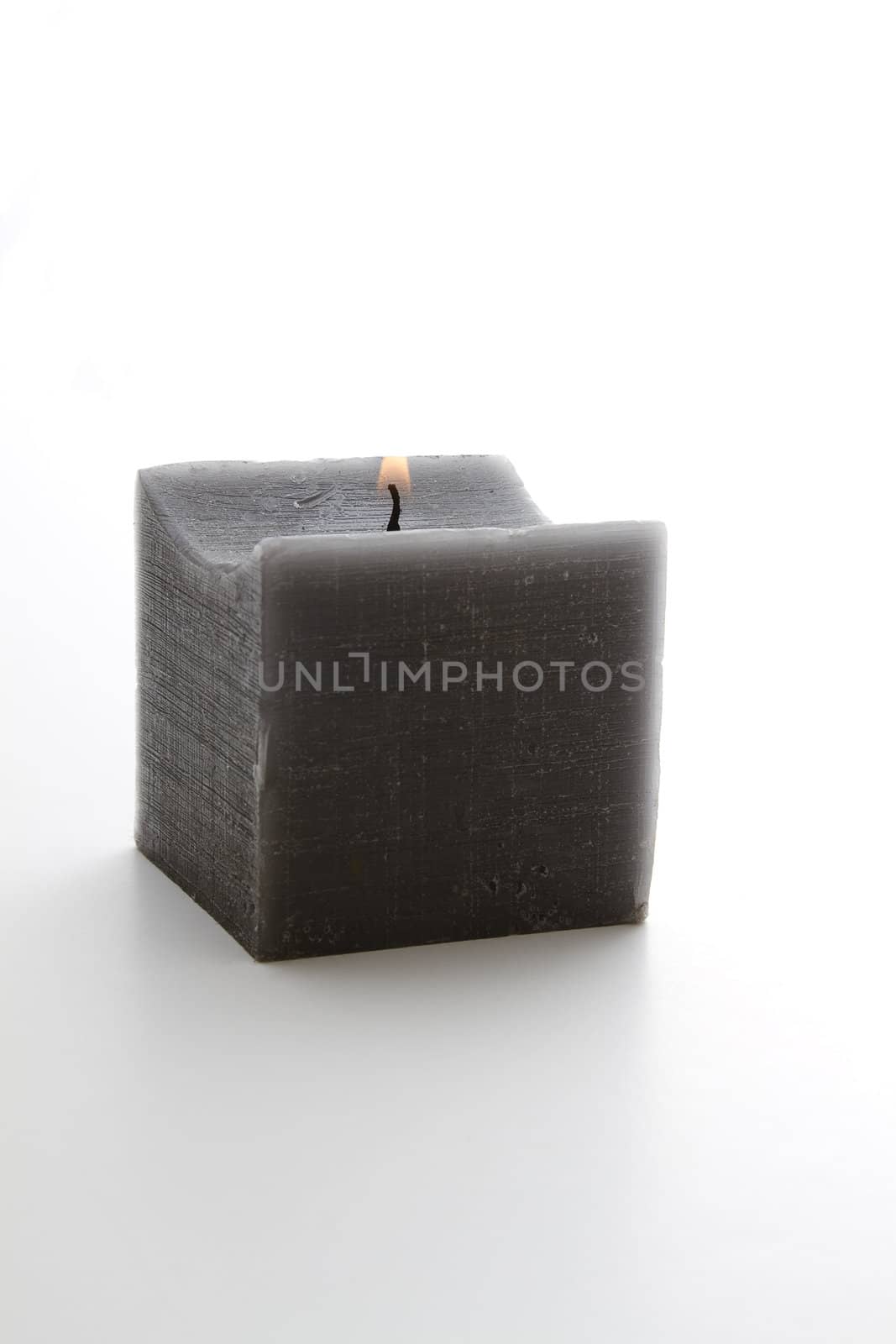 lit square gray candle against white background