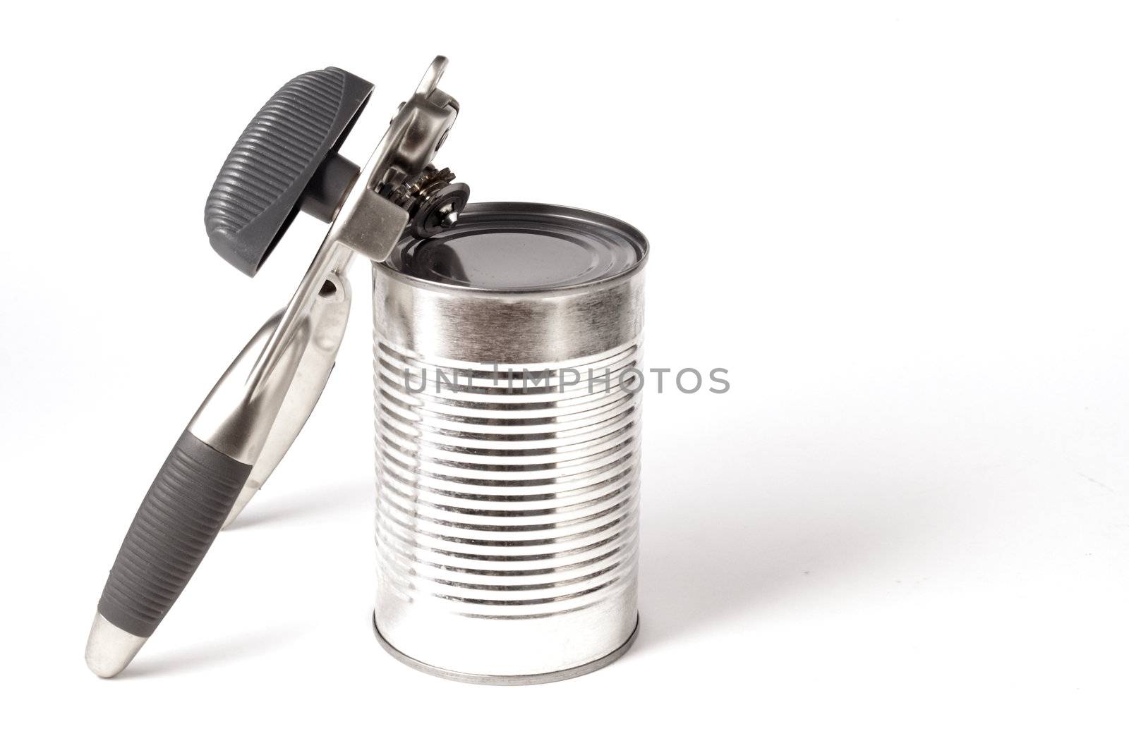 An isolated tin can with a can opening tool leaning up on it.