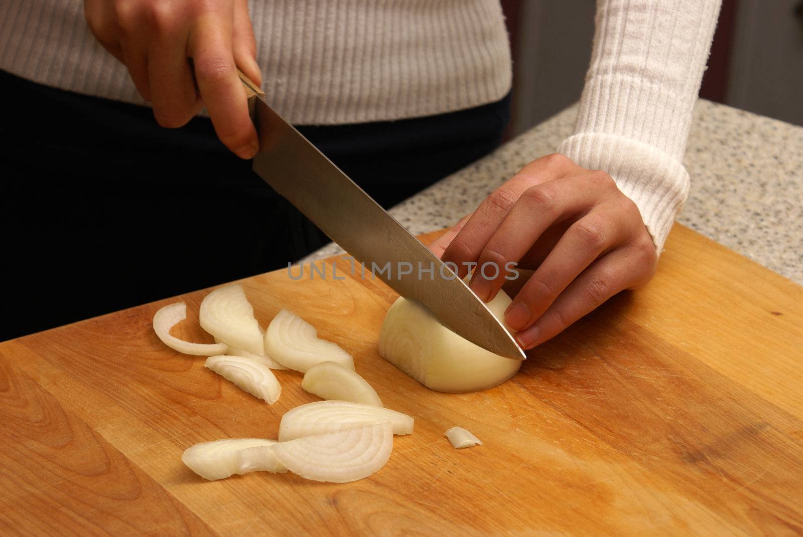 A woman chopping an onion on a cutting board.