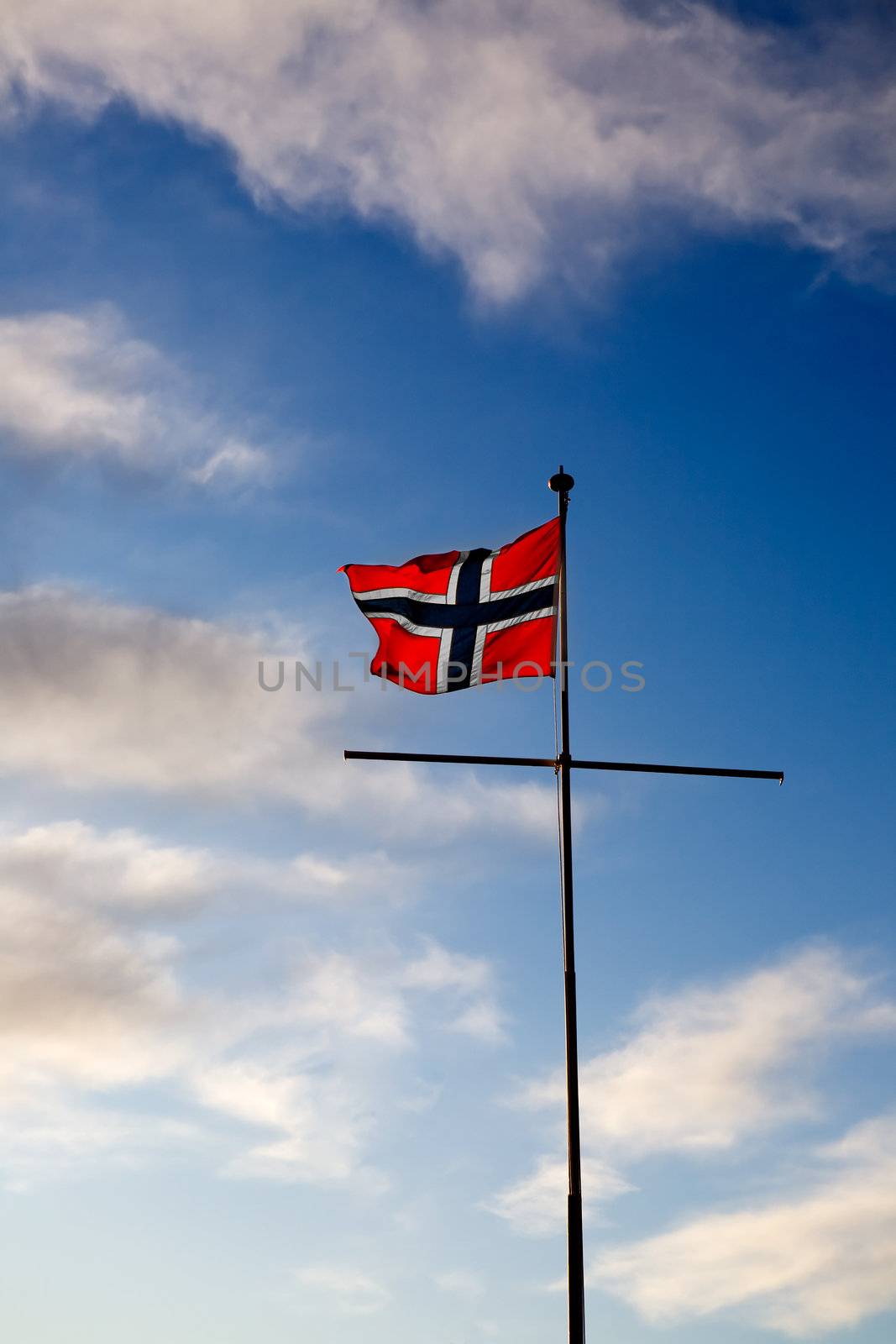 A norwegian flag blowing in the wind against a blue sky