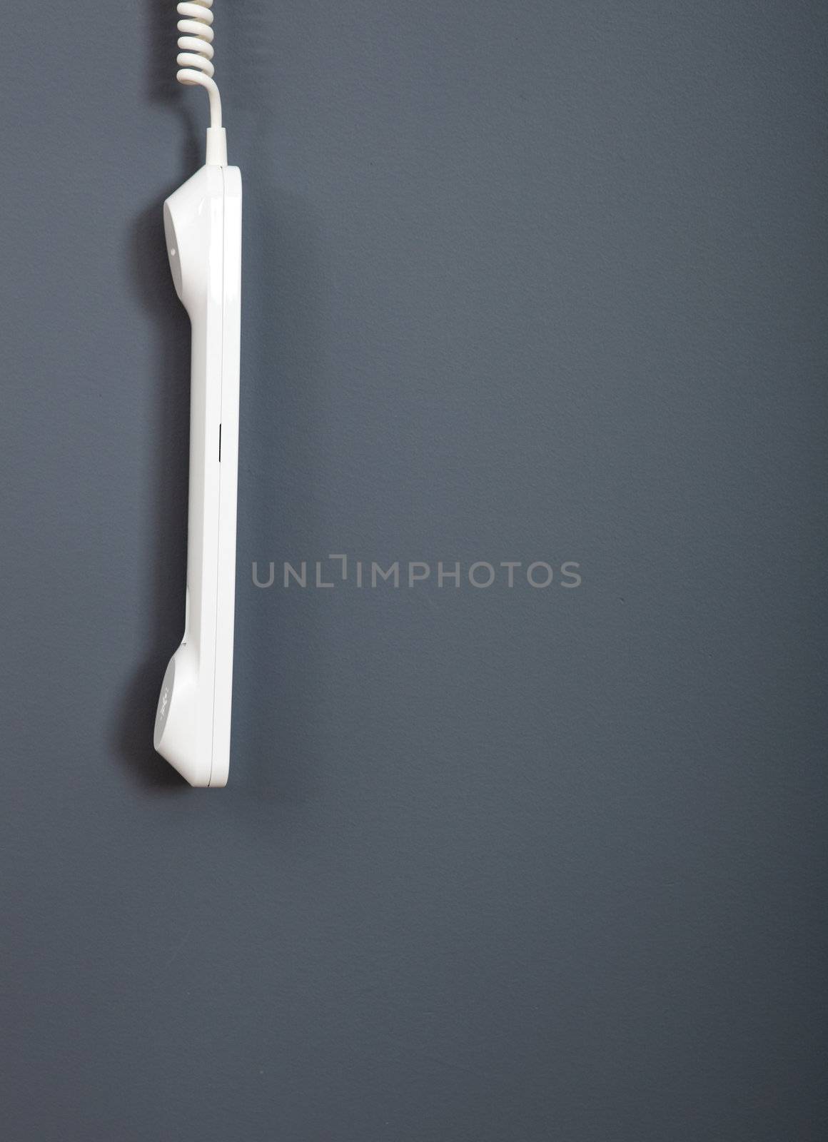 White phone hanging out over a grey wall
