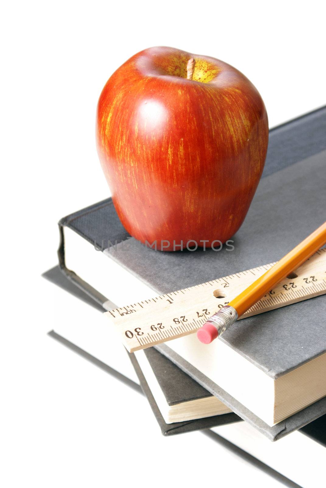 A few school books with an apple, ruler, and pencil.