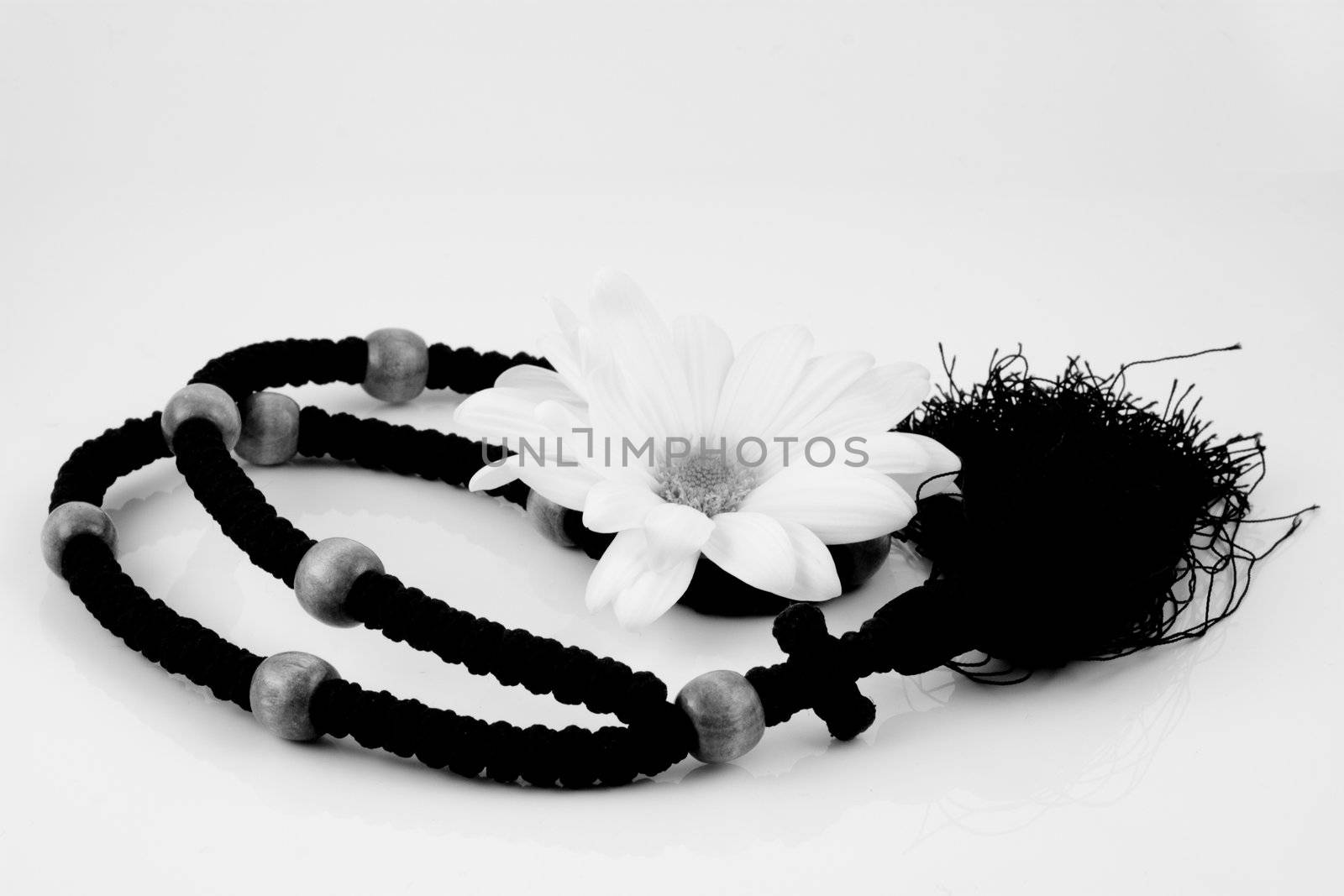 Black & white photo of rosary with white flower
