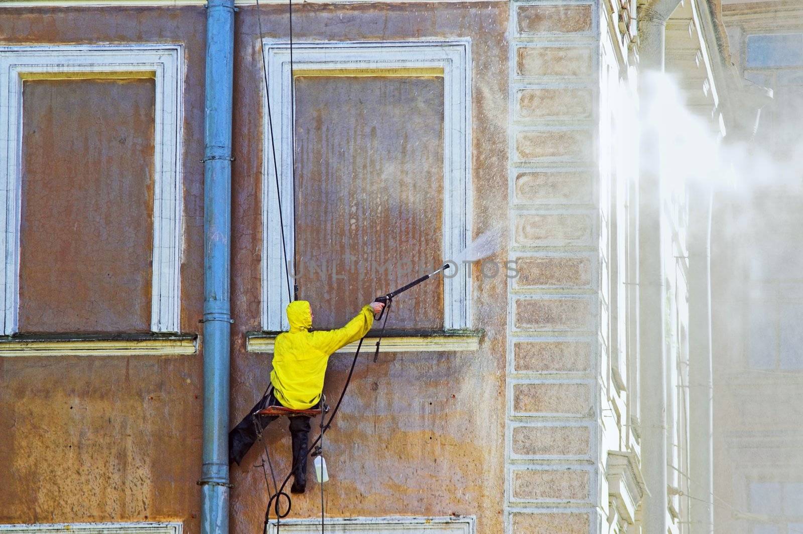 Cleaning service worker washing old building facade