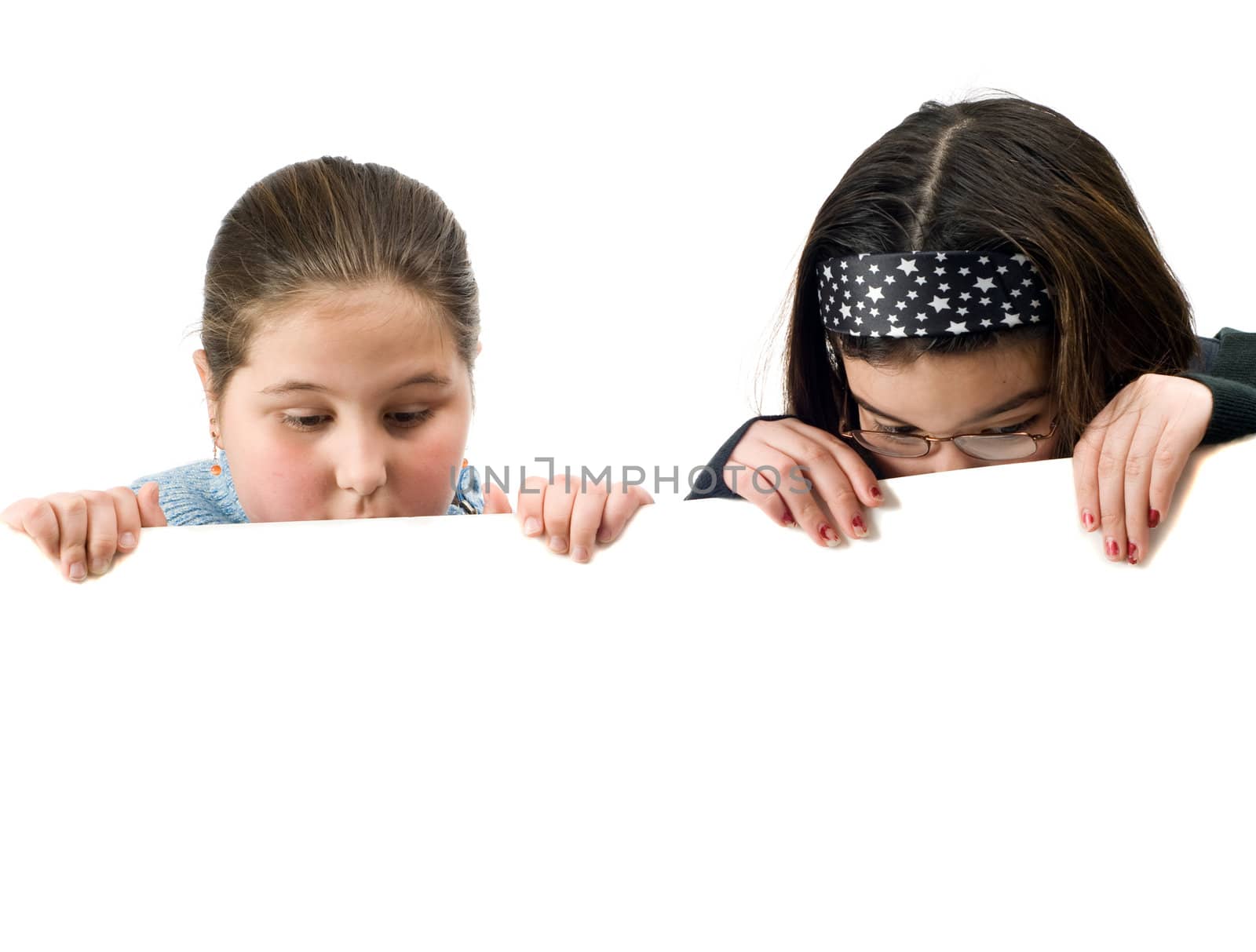 Two young girls looking over a white wall at something