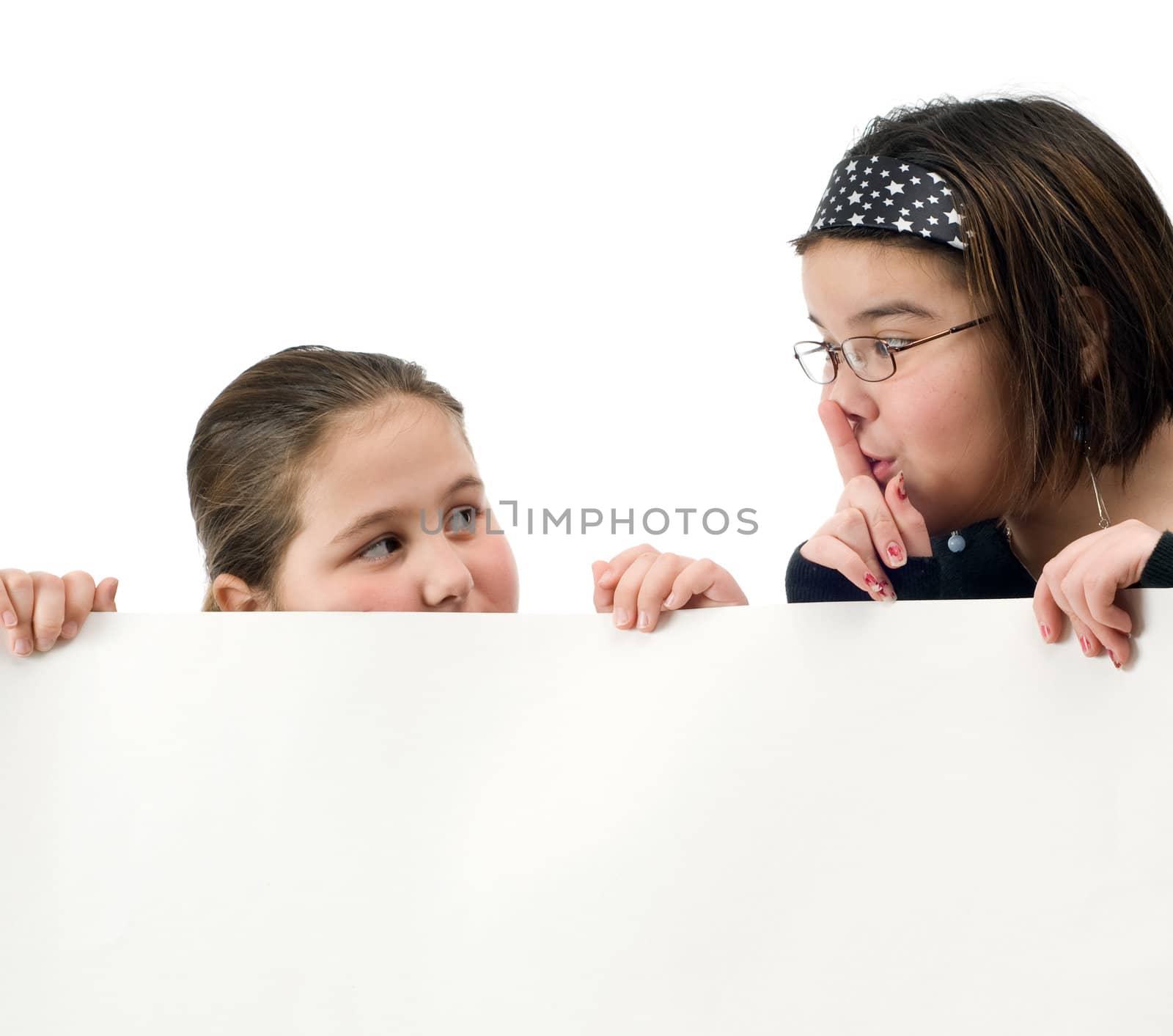 Two young girl trying to spy over a white wall, isolated against a white background