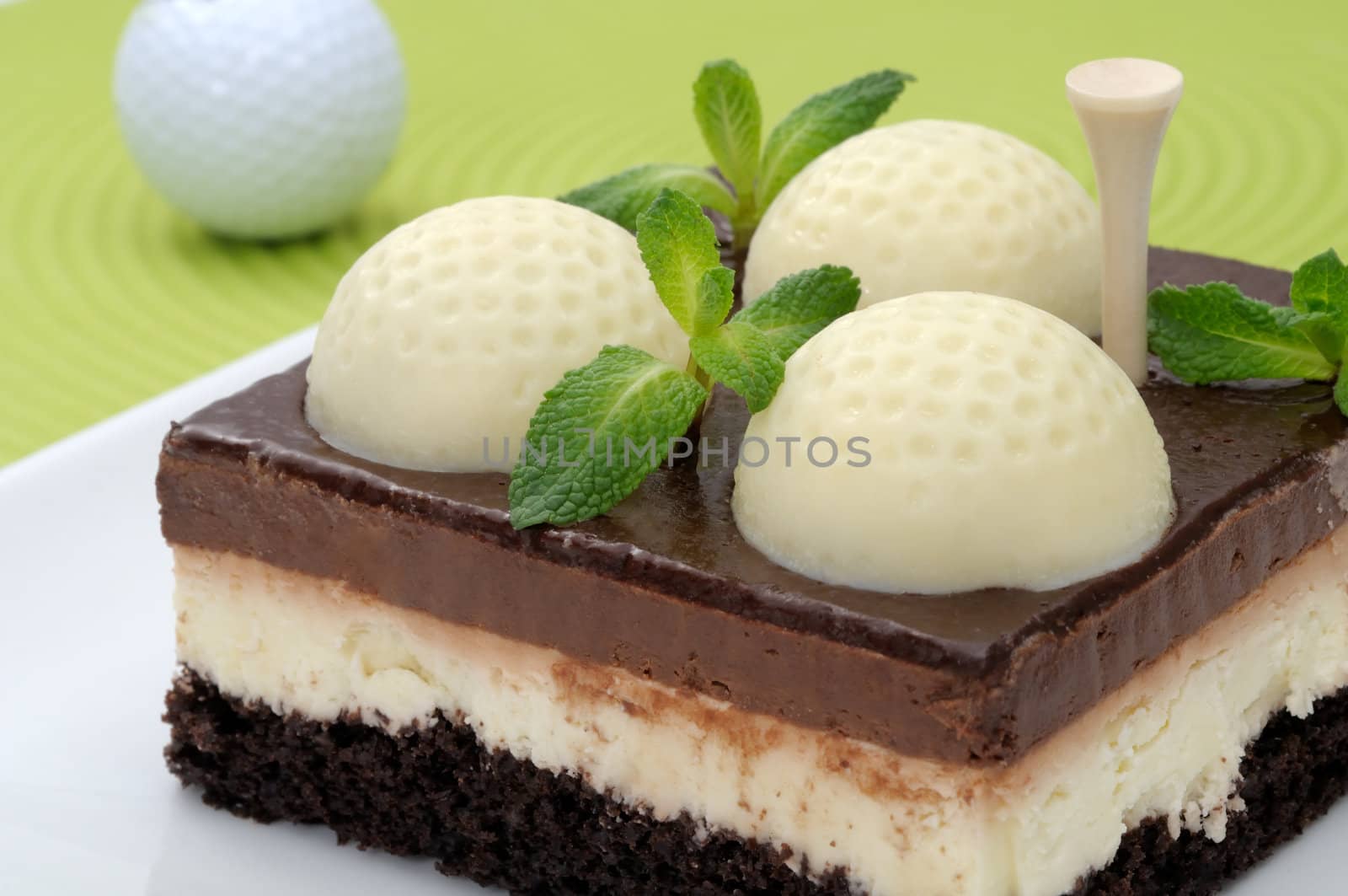 Fanciful chocolate golf cake with mint leaves on a green mat