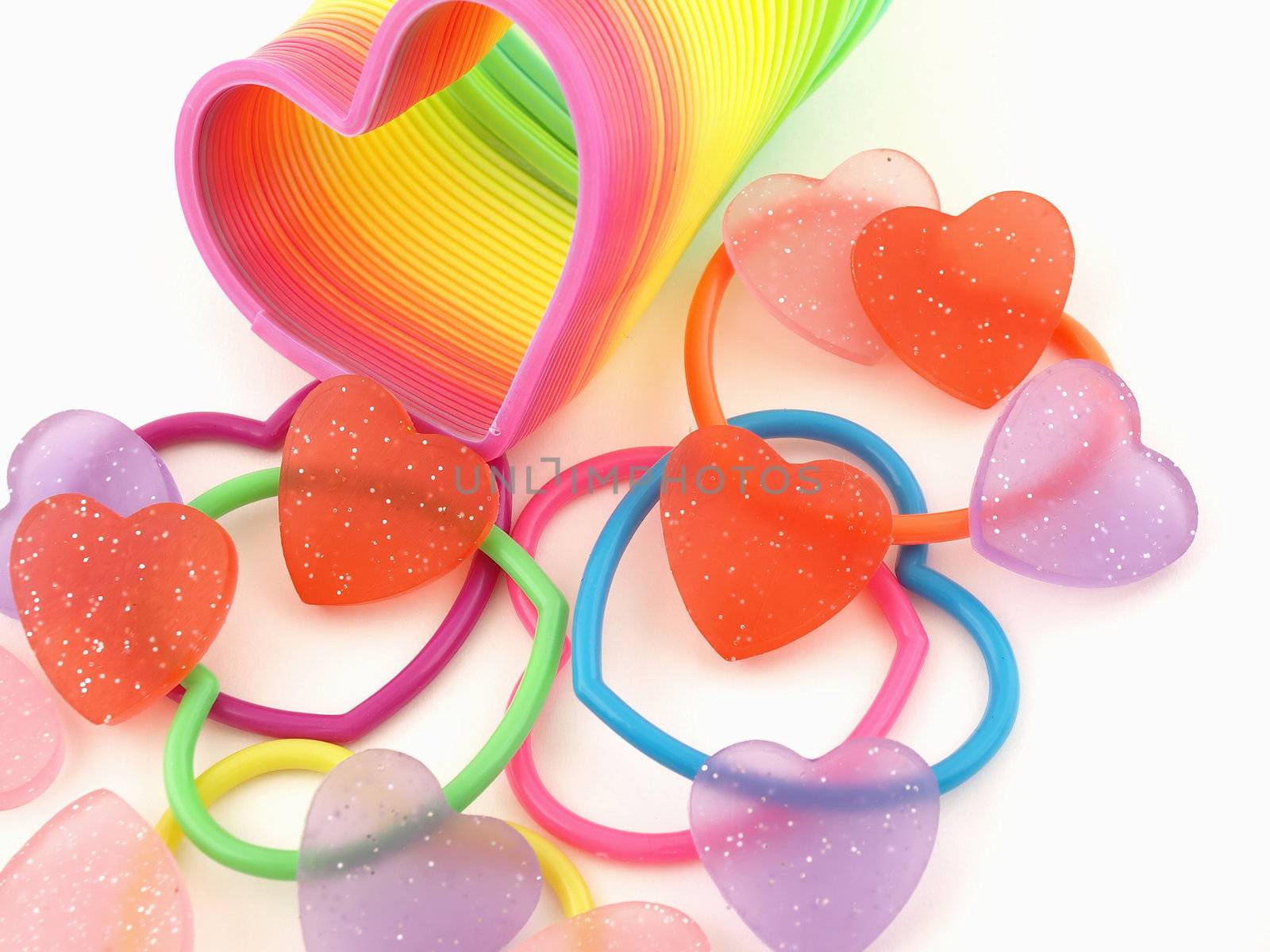 Red Hearts scattered with colorful hearts and slinky isolated on a white background