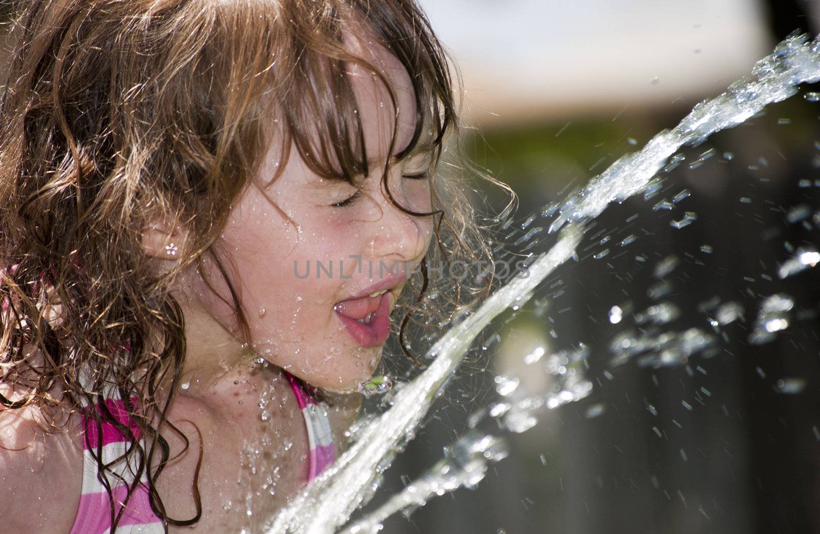 Girl playing outside with water on the summer