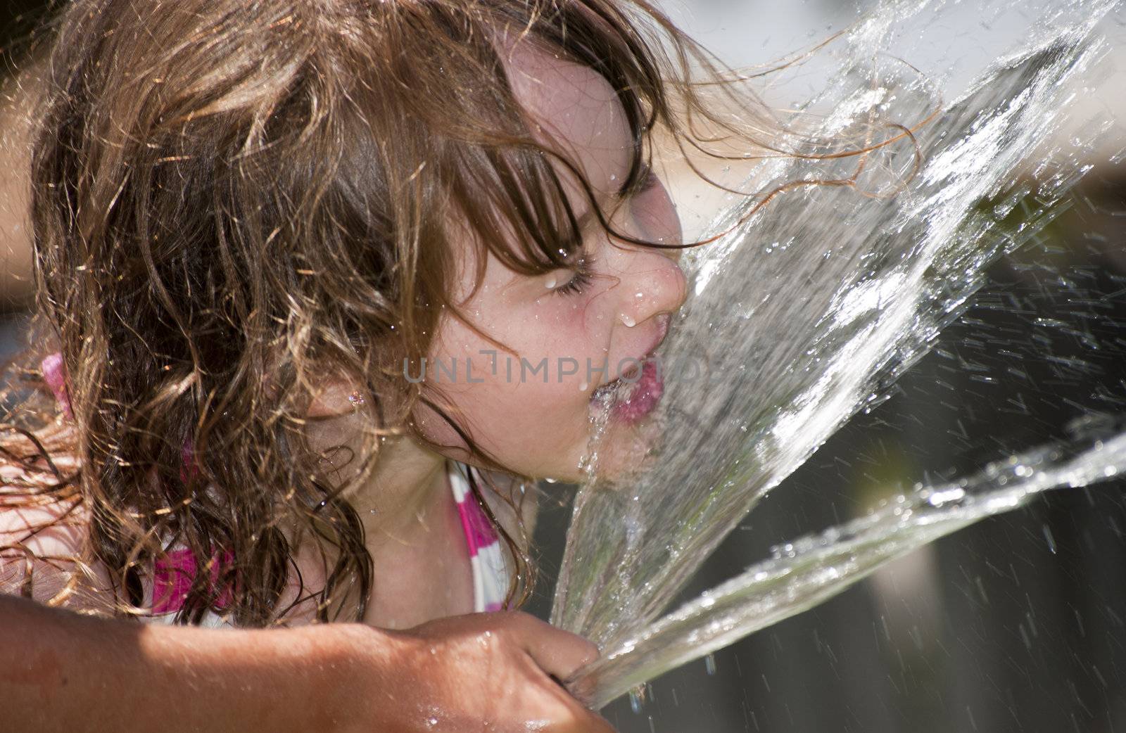 Girl playing outside with water on the summer