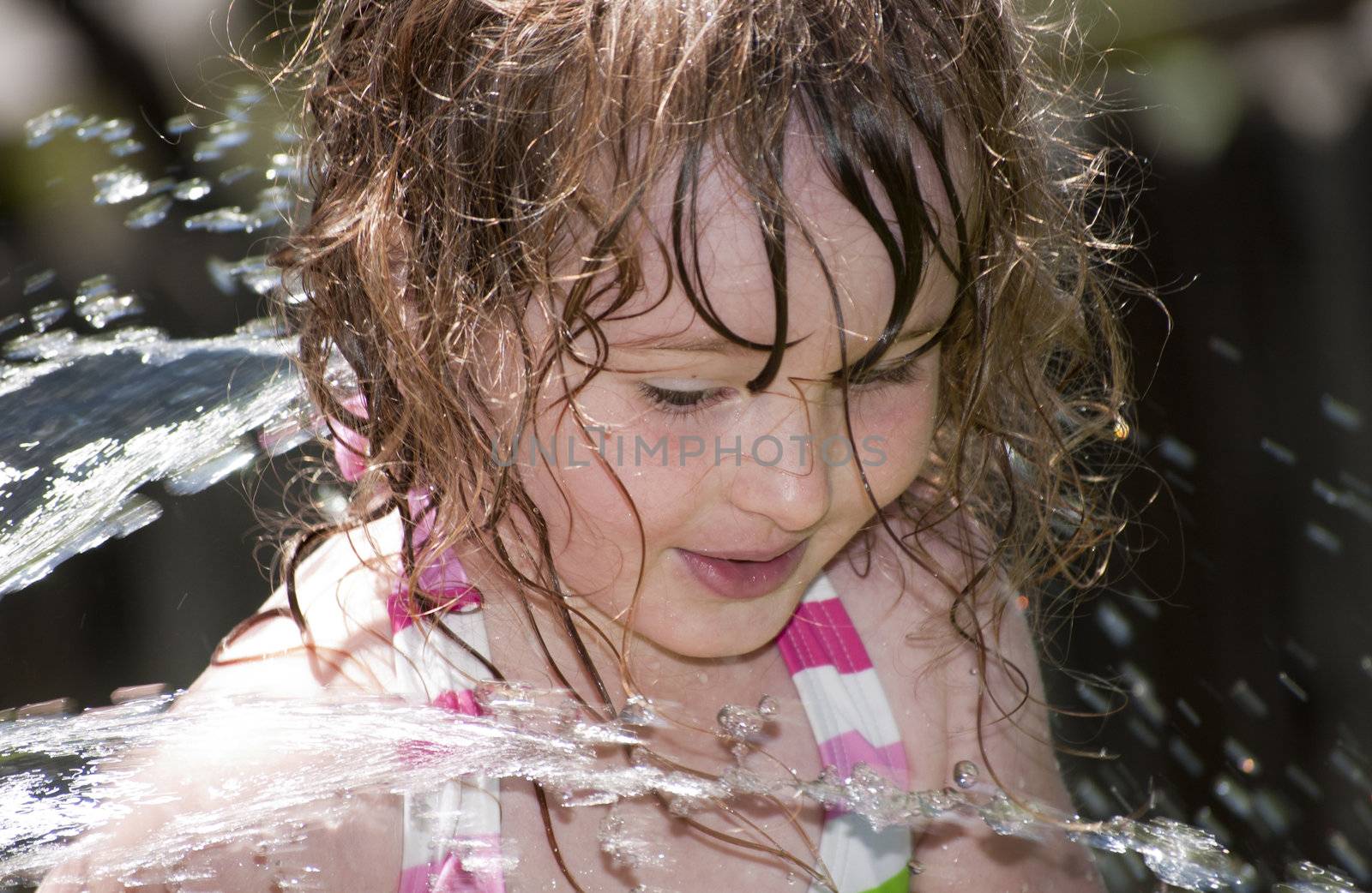 Girl playing outside with water on the summer