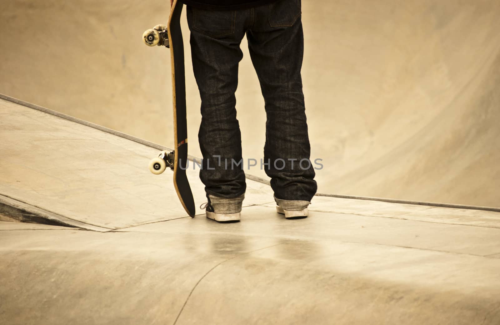 Teenager holding his skateboard at local skatepark