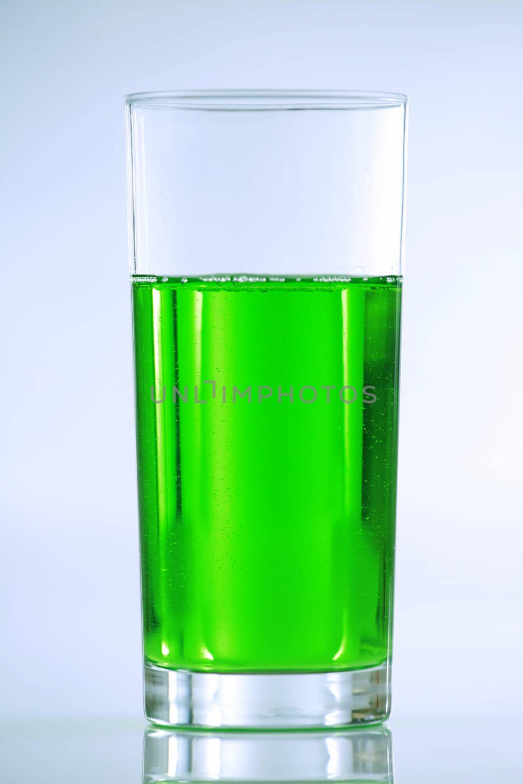 Green drink in tall glass with muted blue tones in background