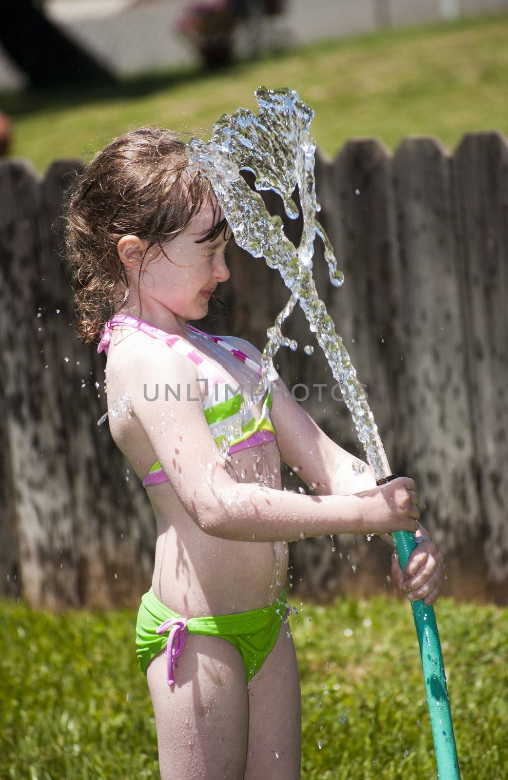 Girl playing outside with water on the summer