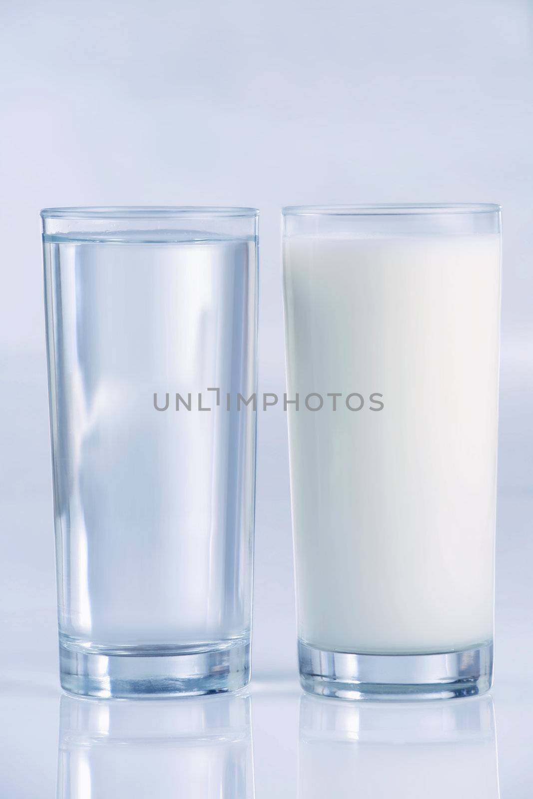 Glass of water and milk, side by side, with blue tones,. Shallow DOF