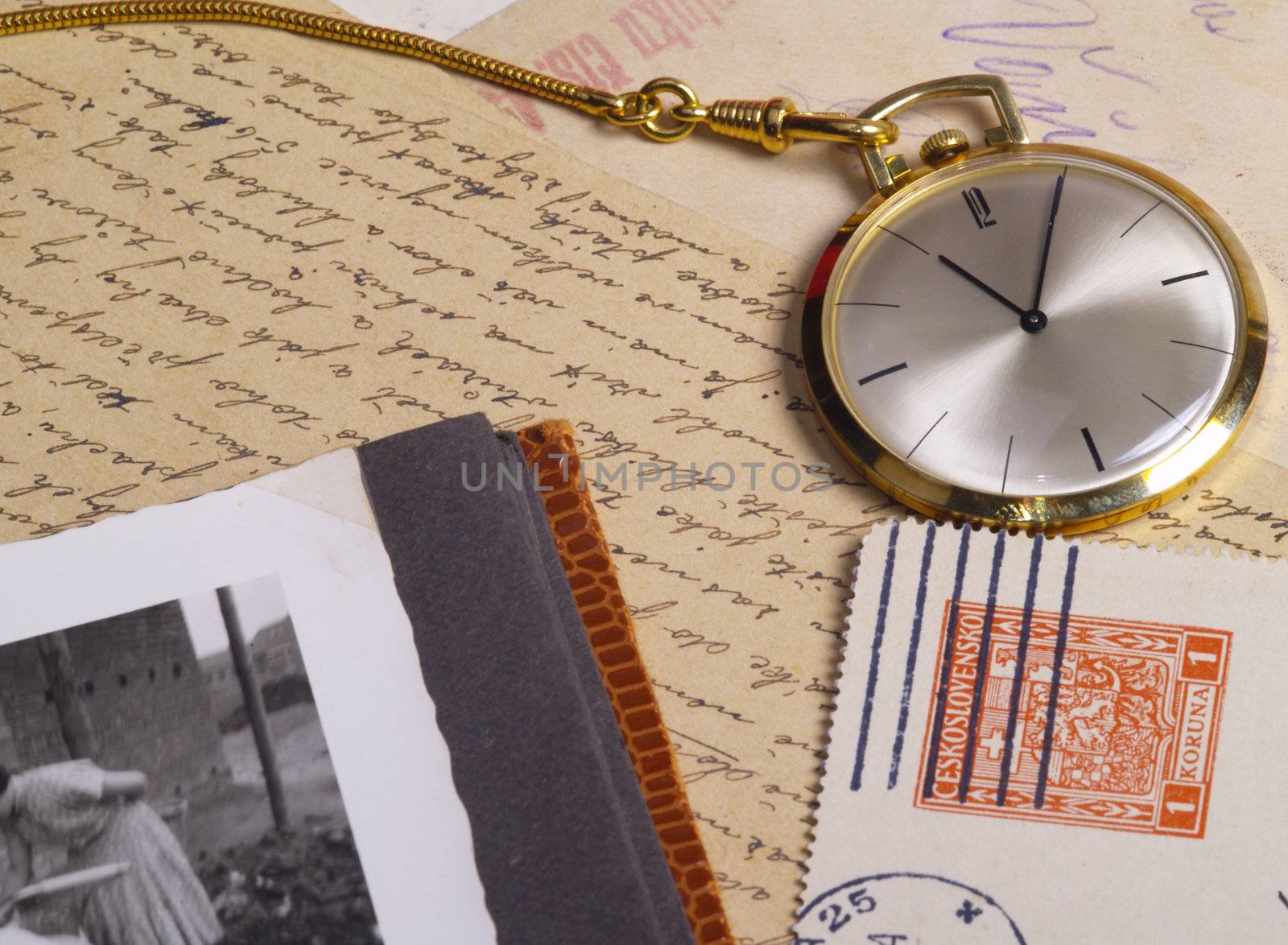 pocket watch over old postcards and photo album