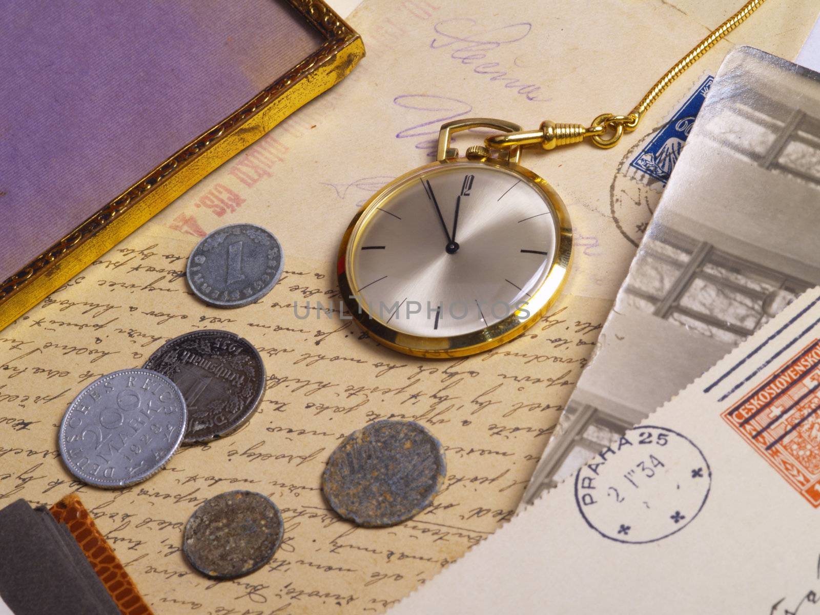 pocket watch and coins over old postcards and photo album