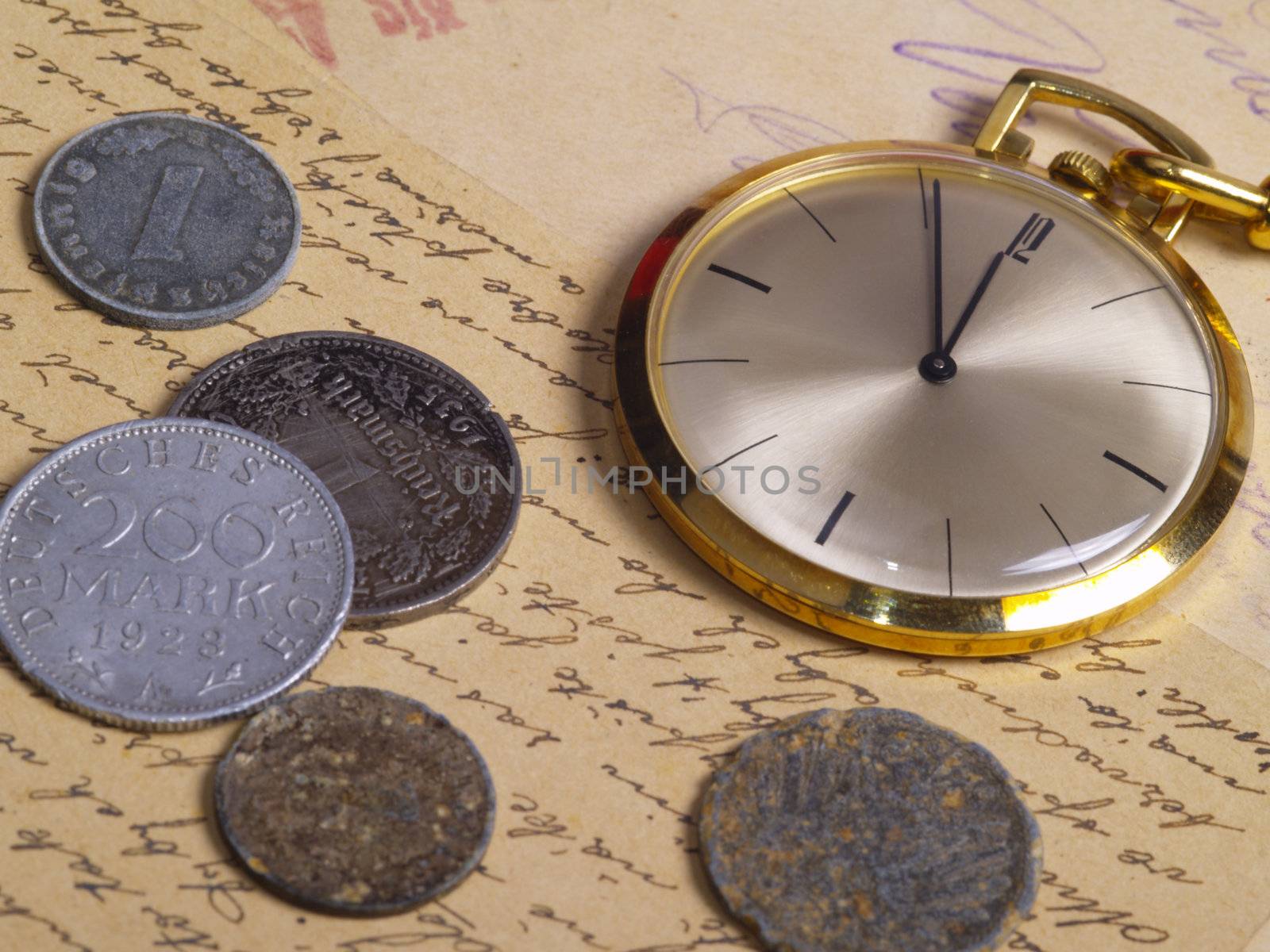 pocket watch and coins over old postcards