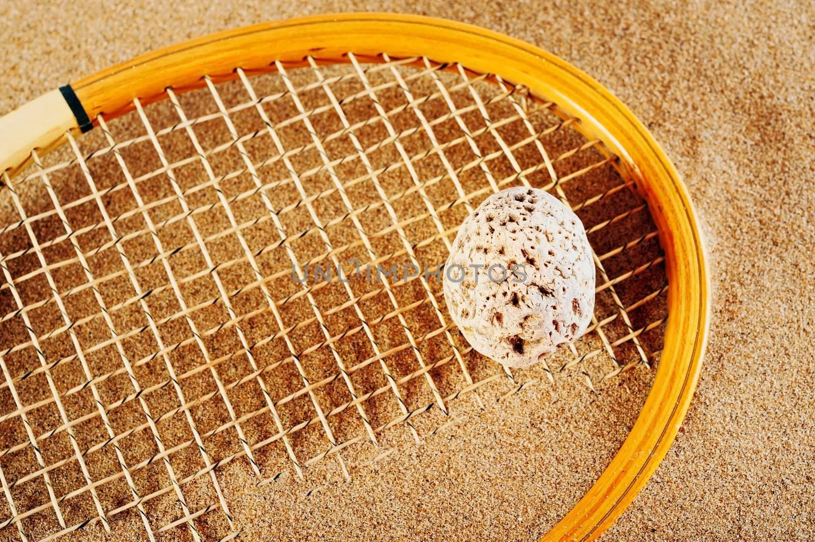 Old tennis racket on a beach in sand in the summer