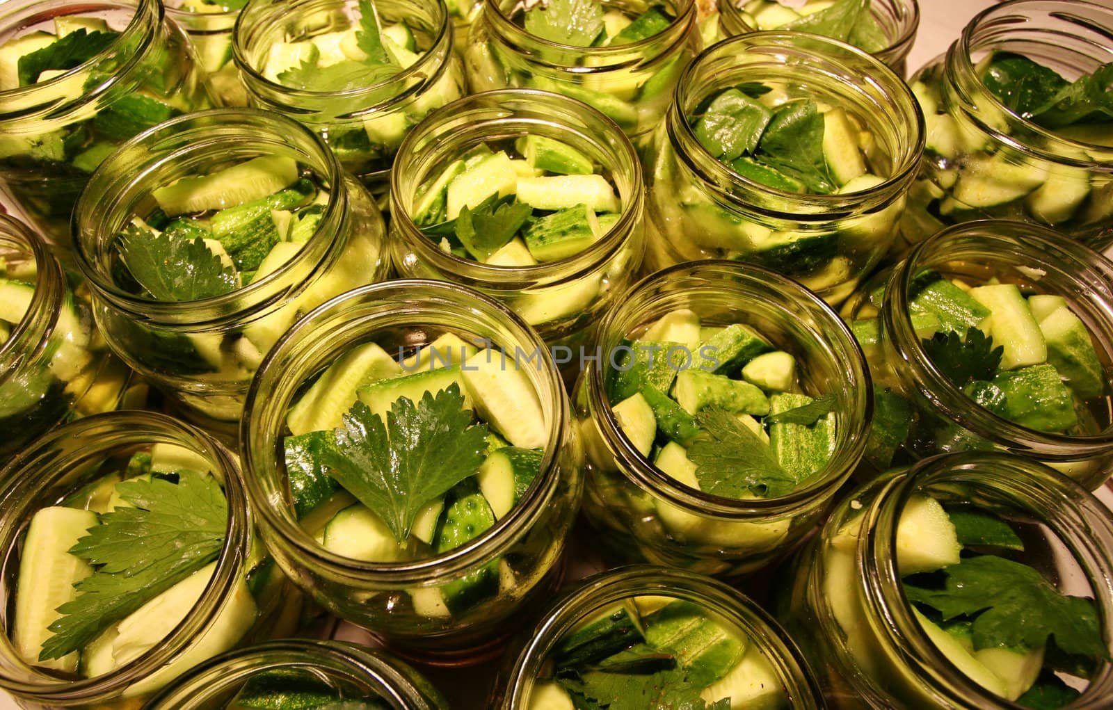 Glass jars filled with delicious green and tasty preserved cucumbers
