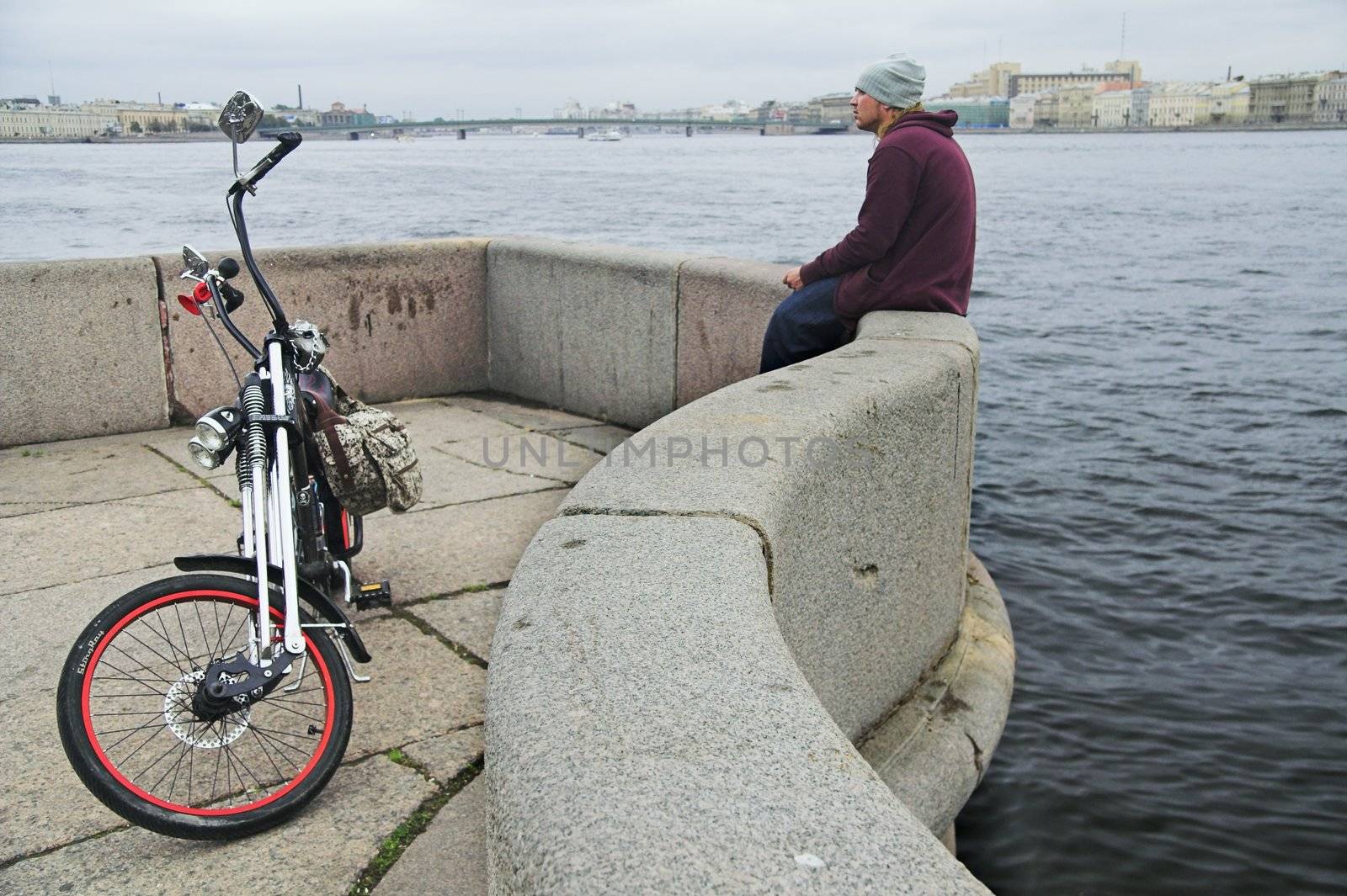 cyclist and his bicycle on granite river embankment