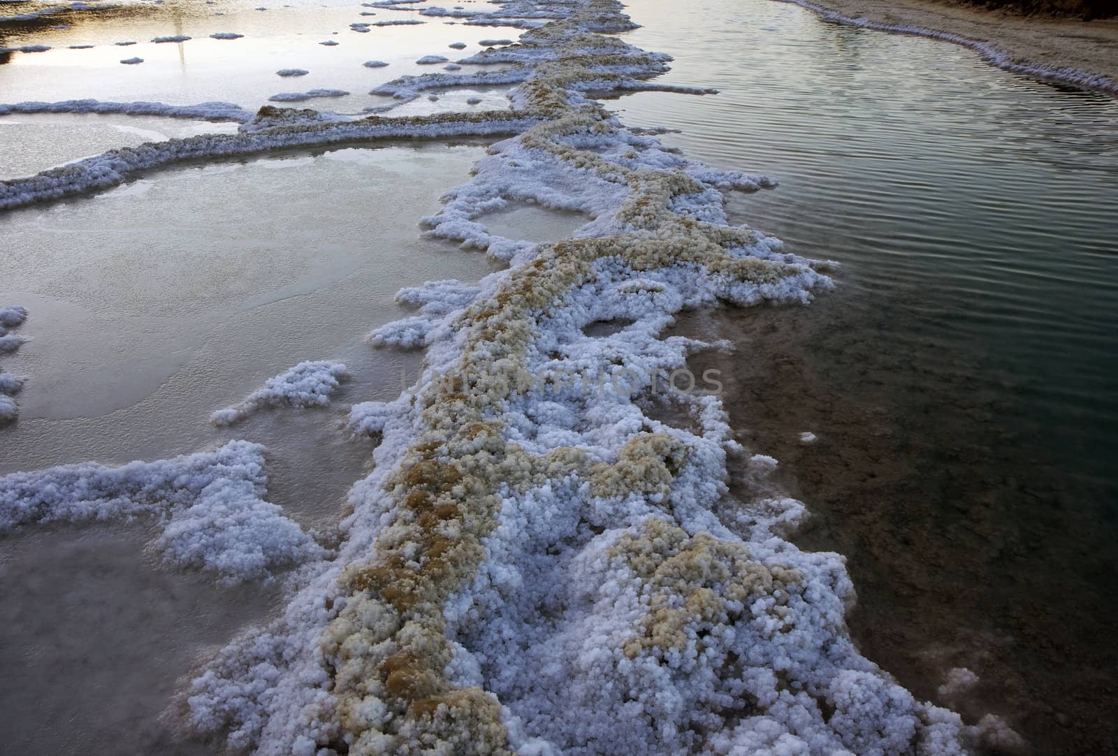 The water of the dead sea with salty paths at sunset