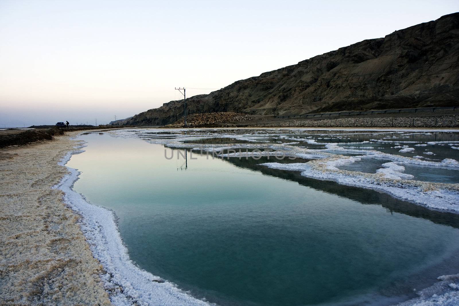 The water of the dead sea with salty paths at sunset