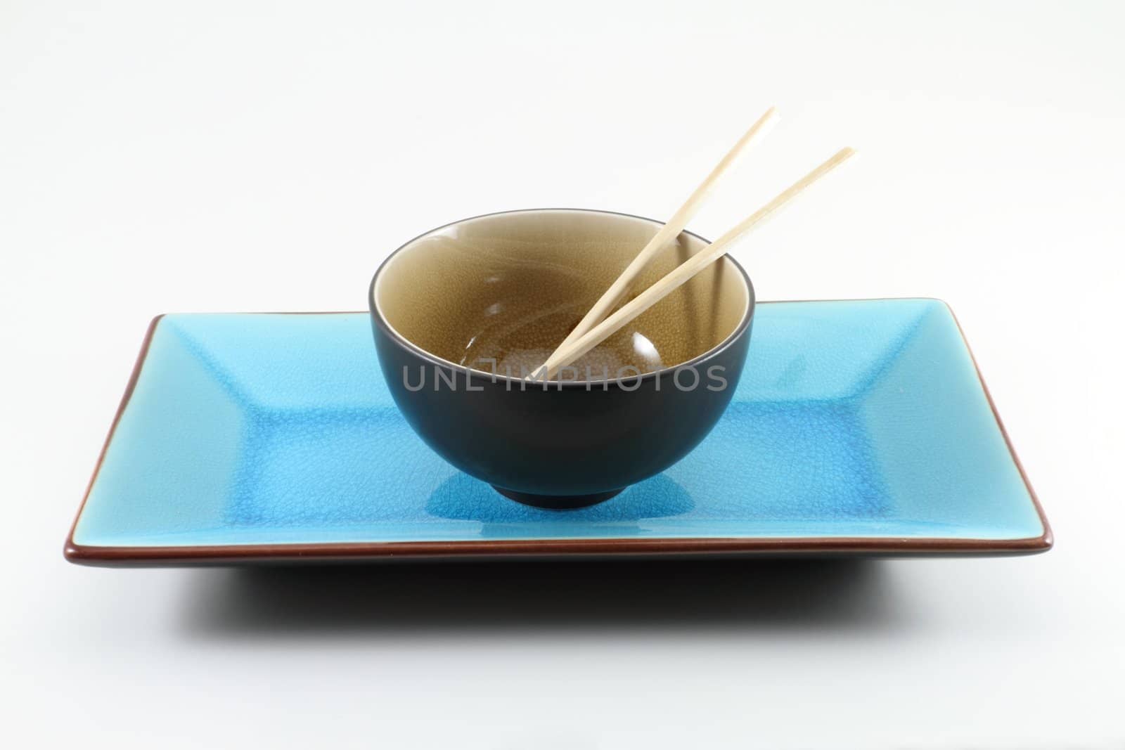 Traditional oriental table setting with chopsticks, rice bowl, and plate.