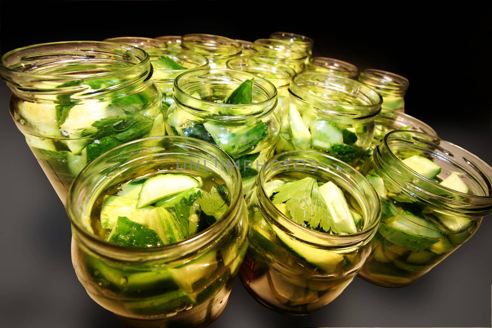 Glass jars filled with delicious green and tasty preserved cucumbers