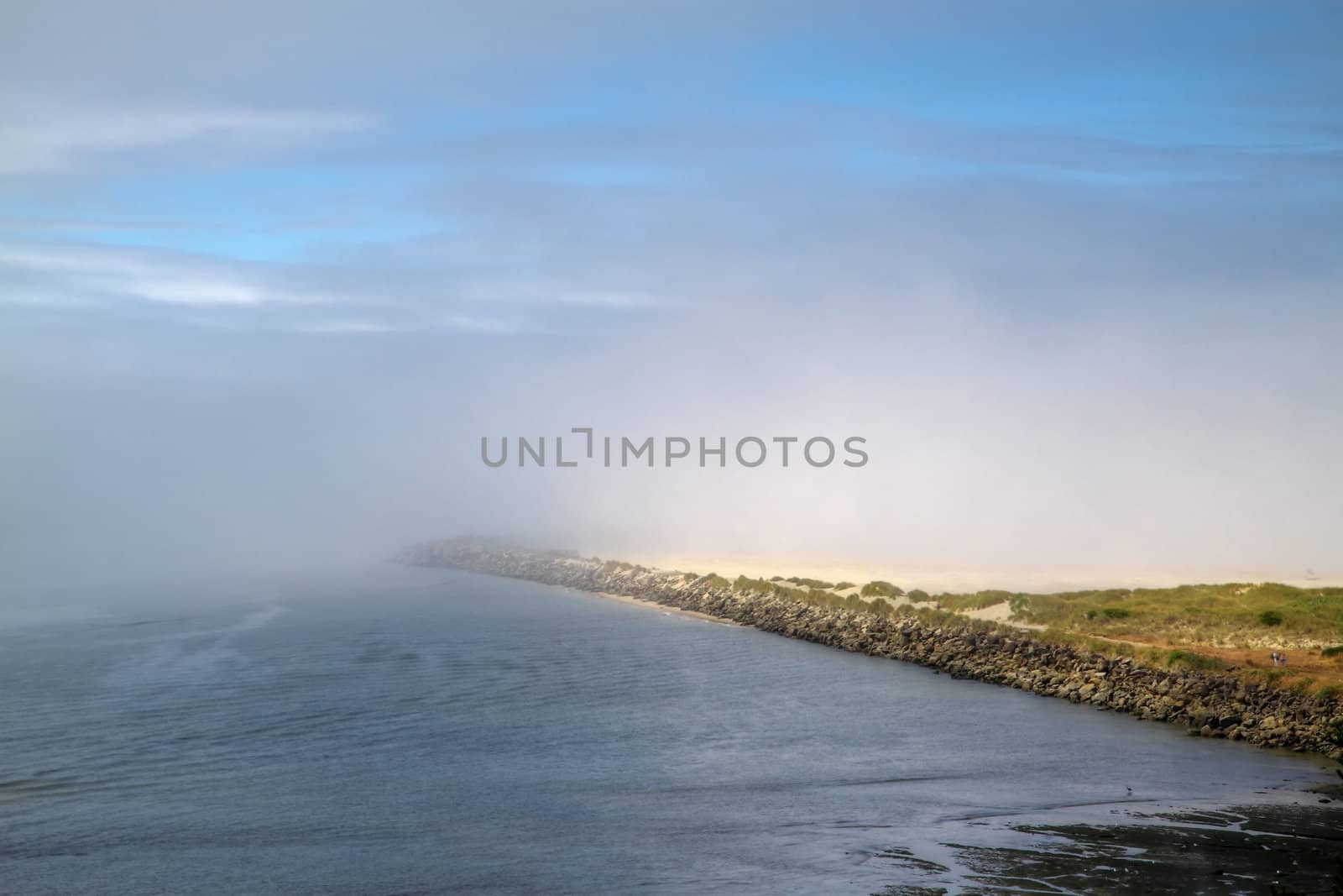 Blue sky and fog over a sandy beach breaker