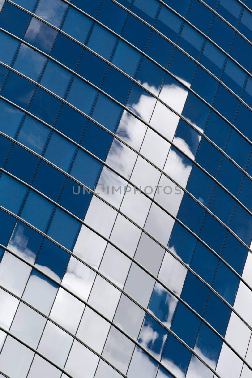 Skyscraper facade with reflection of white clouds and blue sky