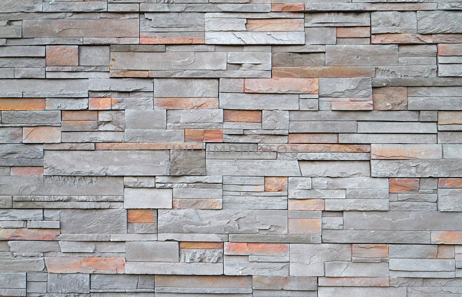 Gray, brown, red flat stone wall in a random pattern